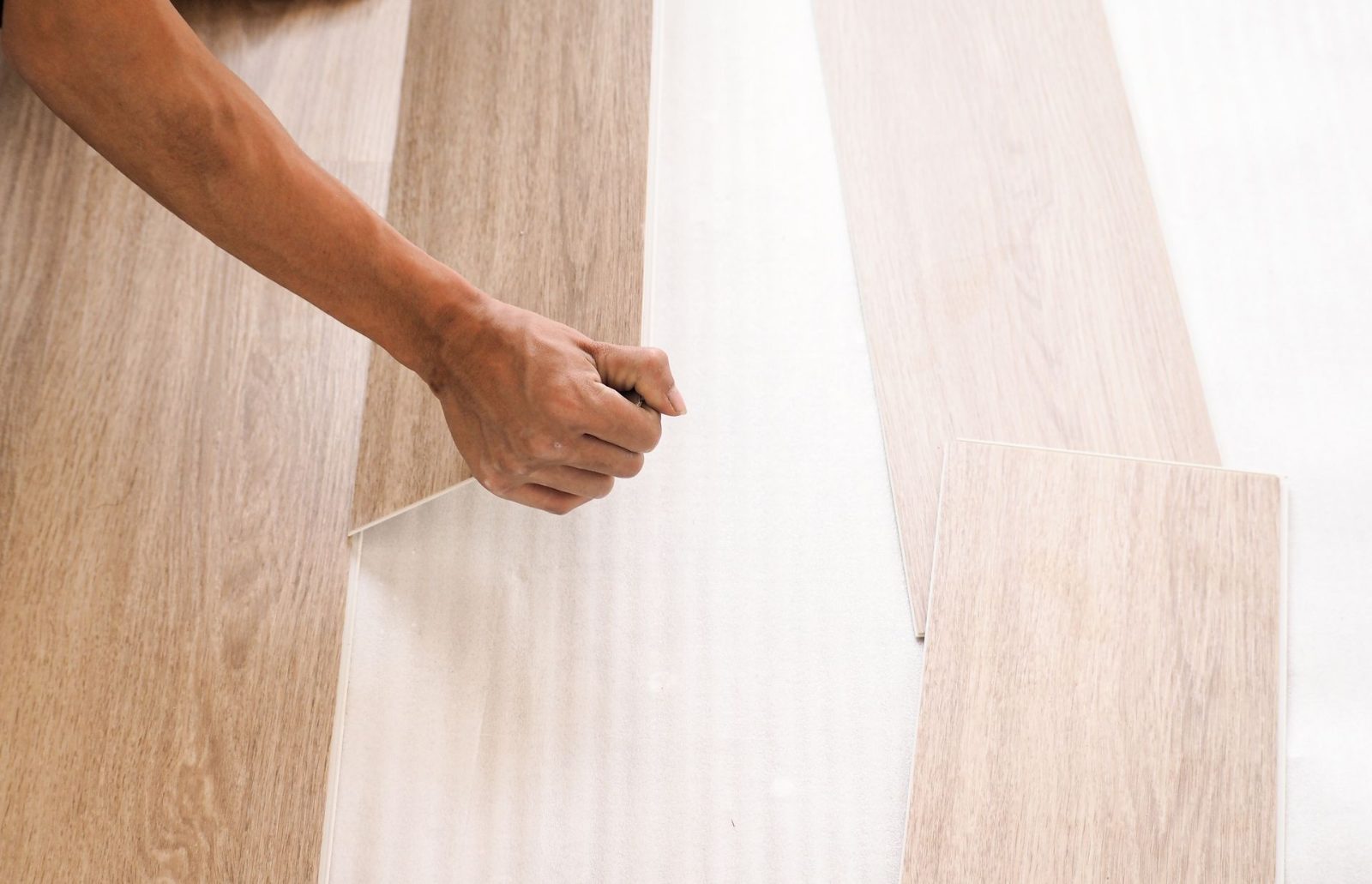 Installer fitting a light wood-look plank into place